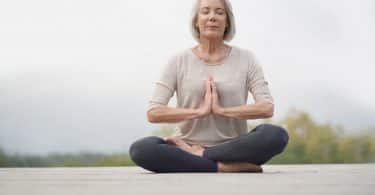 Mulher mais velha sentada em pose de meditação.