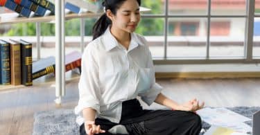 Garota chinesa meditando na sala de casa.