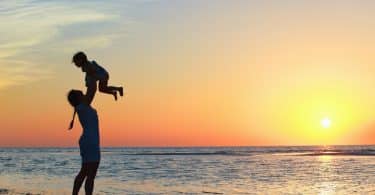 Mãe levantando filho na beira da praia