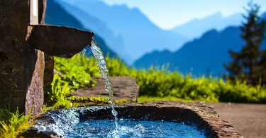 Fonte de água com paisagem de montanhas ao fundo.