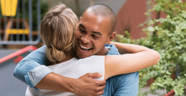 Um homem sorrindo e abraçando uma mulher