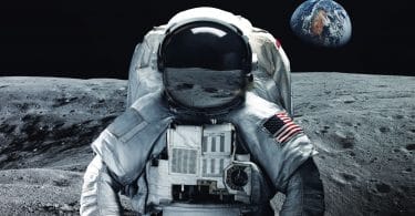 Astronauta com uniforme e bandeira dos Estados Unidos na Lua. Ao fundo é possível ver a Terra.