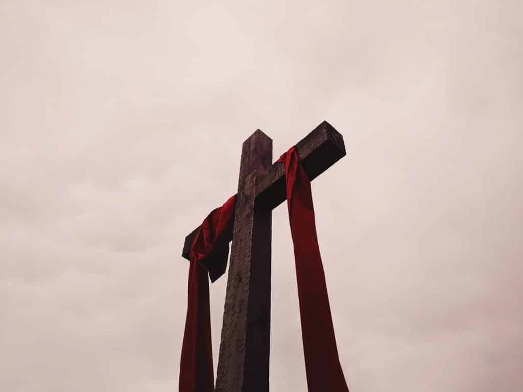 Cruz de madeira com um lenço vermelho vista de baixo.