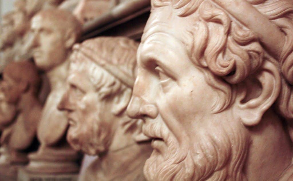 Esculturas esculpidas em mármore de filósofos da Grécia Antiga, vistas de perfil.
