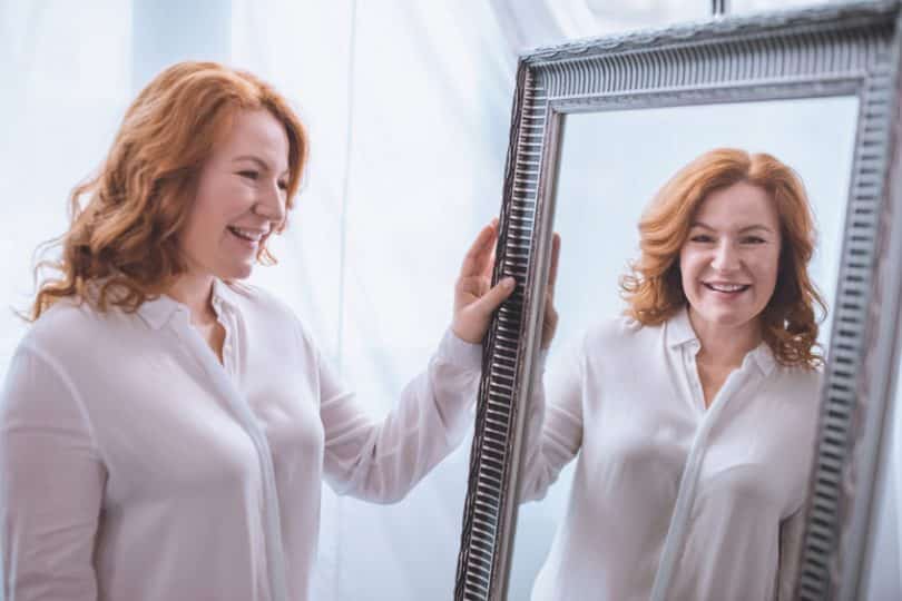 Mulher em frente ao espelho sorrindo