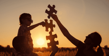 Família montando quebra-cabeça juntos durante pôr do sol