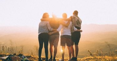 Quatro amigos se abraçando vendo o pôr do sol