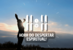 Hora igual 11:11 e texto "Hora do despertar espiritual!" aplicado por cima de foto de uma mulher em pé, com os braços levantados e contemplando a natureza. Ao fundo, há o céu com nuvens e a luz do pôr do sol.