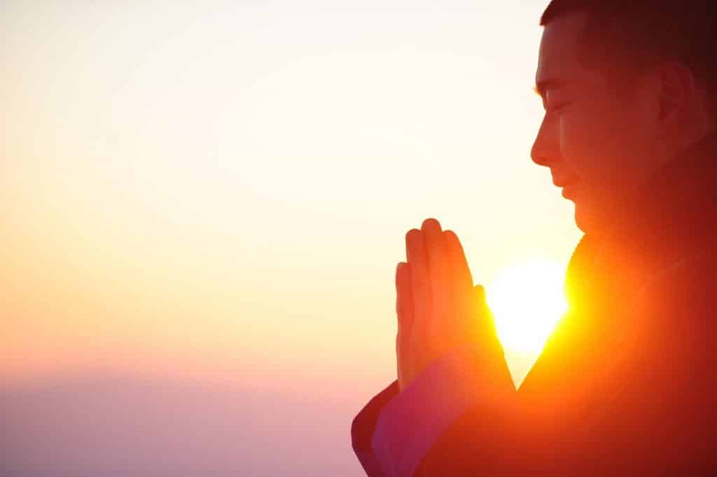 Homem meditando diante do pôr do Sol