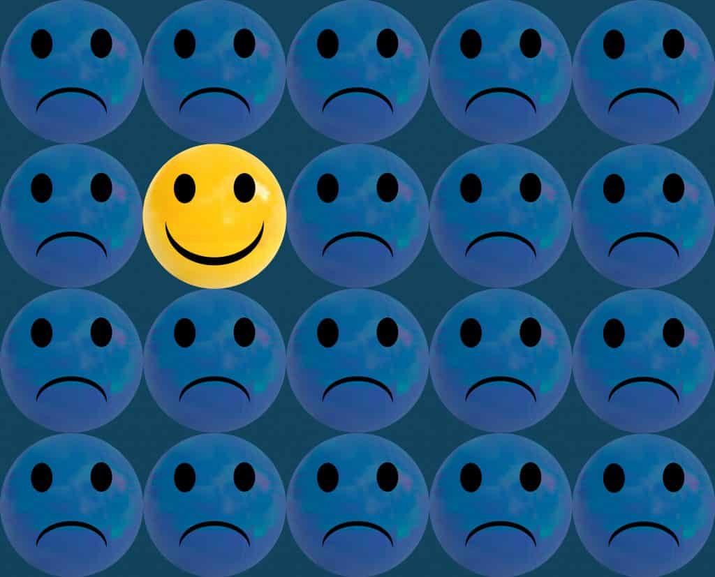 Ilustração de rostos tristes com um rosto feliz no meio