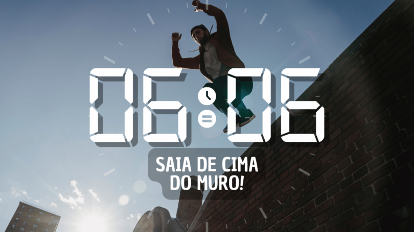 Hora igual 06:06 e texto "Saia de cima do muro!" aplicado por cima de foto de um homem pulando um muro de tijolos. Ao fundo, há um céu azul e a luz do sol.