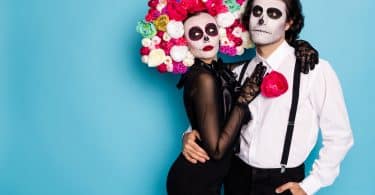 Um homem e uma mulher abraçados e fantasiados com trajes típicos do Día de Los Muertos Mexicano