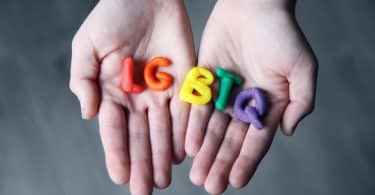 Mãos segurando letras feitas de massinha formando a sigla LGBT