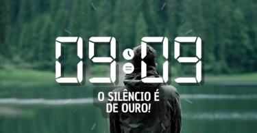 Hora igual 09:09 e texto "O silêncio é de ouro!" aplicado por cima de foto de um homem sozinho de frente para um rio contemplando a natureza em silêncio.