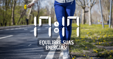 Hora igual 17:17 e texto "Equilibre suas energias!" aplicado por cima de foto das pernas de uma mulher que veste uma calça azul. Ela se equilibra na guia de uma calçada que está coberta de gramas e de flores amarelas. Ela segura pequenas flores amarelas em uma mão. Ao fundo, há uma rua e árvores.