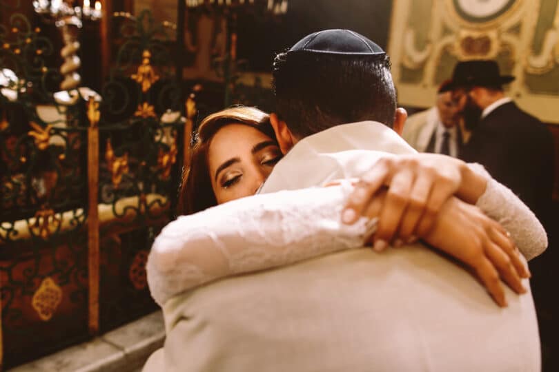 Noivos judeus se abraçando na cerimônia.