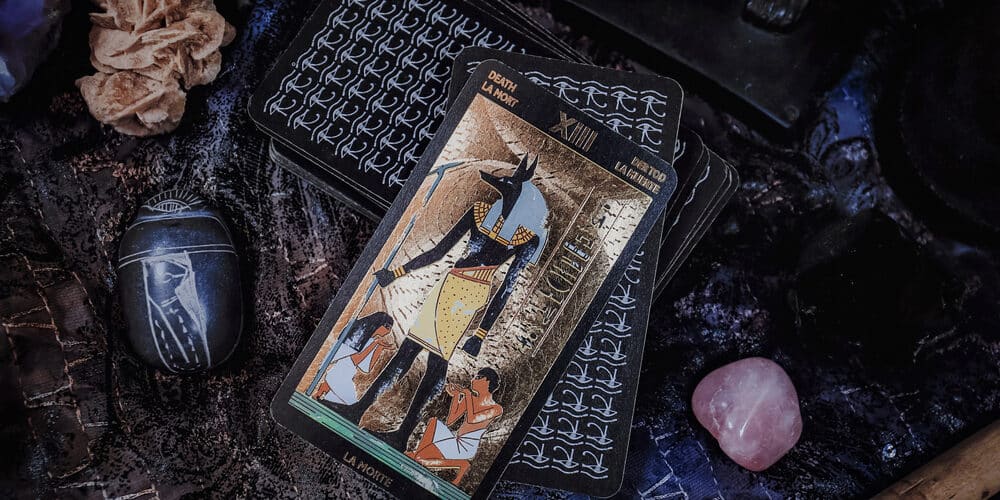 Carta de tarot egípcio sobre uma mesa cheia de cristais e itens egípcios