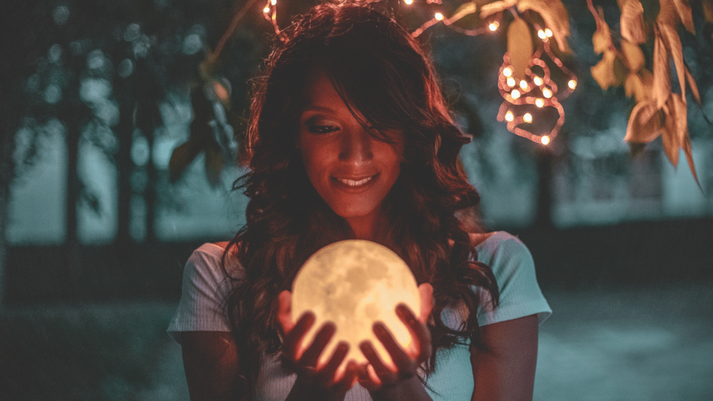 Mulher segurando globo de lua cheia nas mãos. 