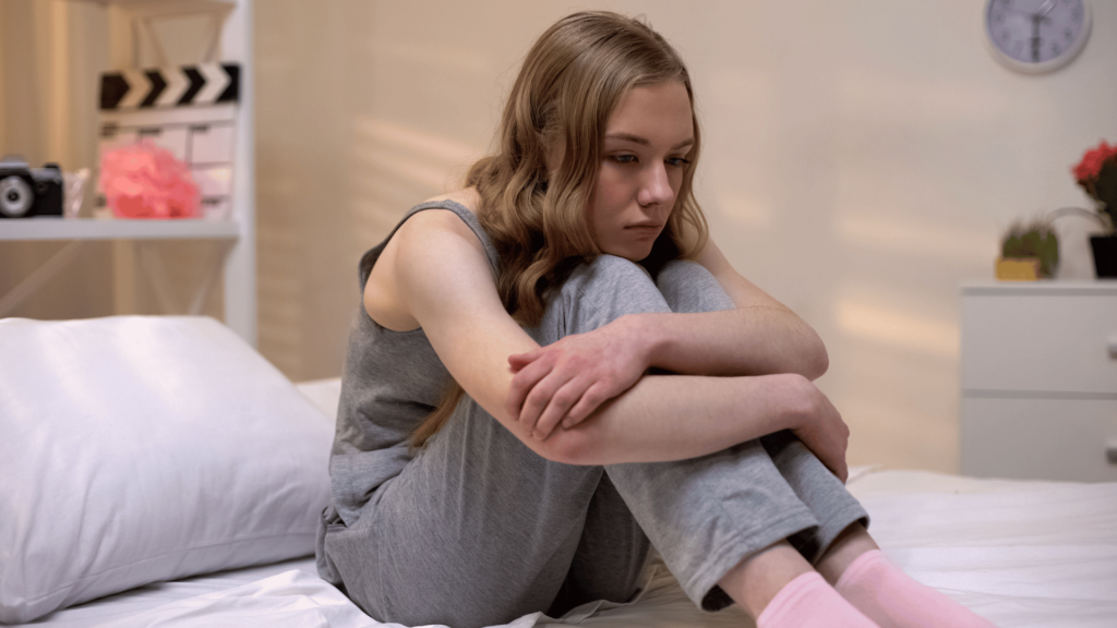 Menina adolescente pensativa sentada sozinha no quarto, sentindo-se abandonada, depressão na puberdade.