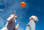 Irmão e irmã soltando um balão no céu.