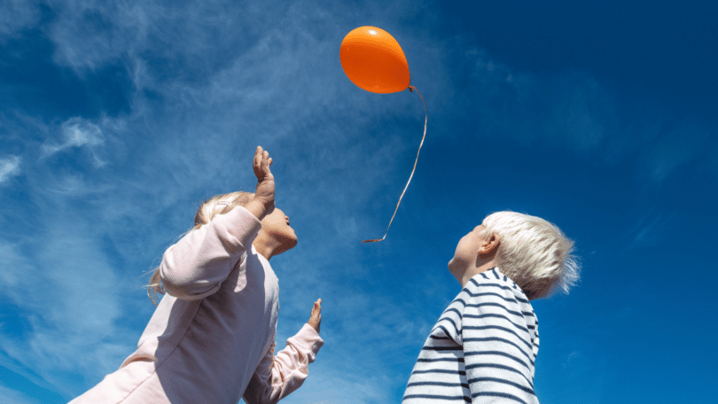 Irmão e irmã soltando um balão no céu.