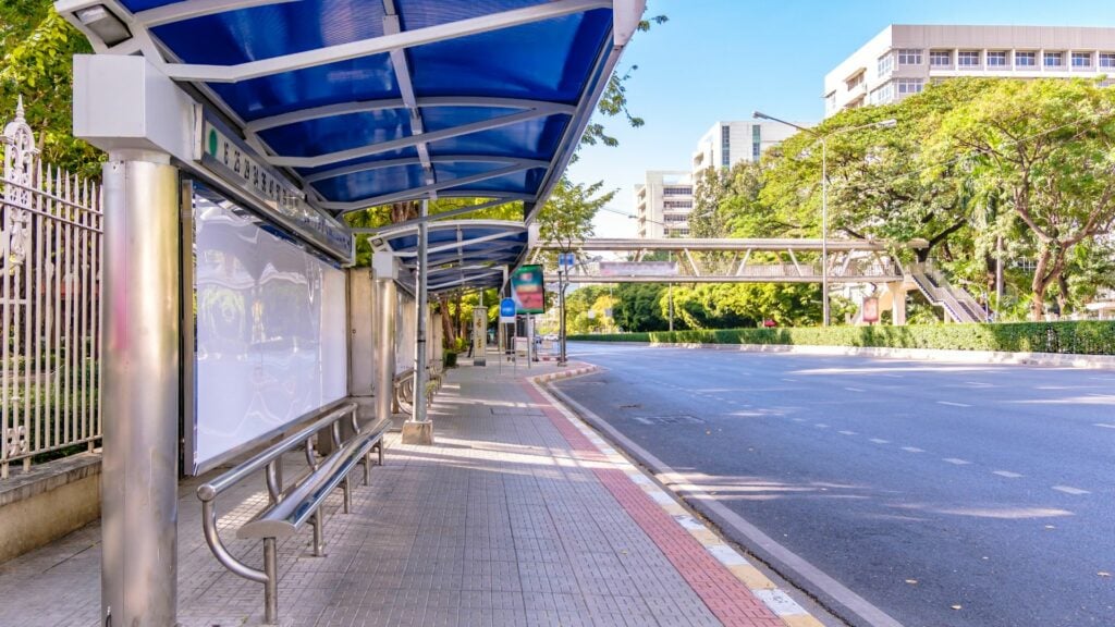 Imagem de dois pontos de ônibus em uma avenida sem movimento de carros e pedestres.
