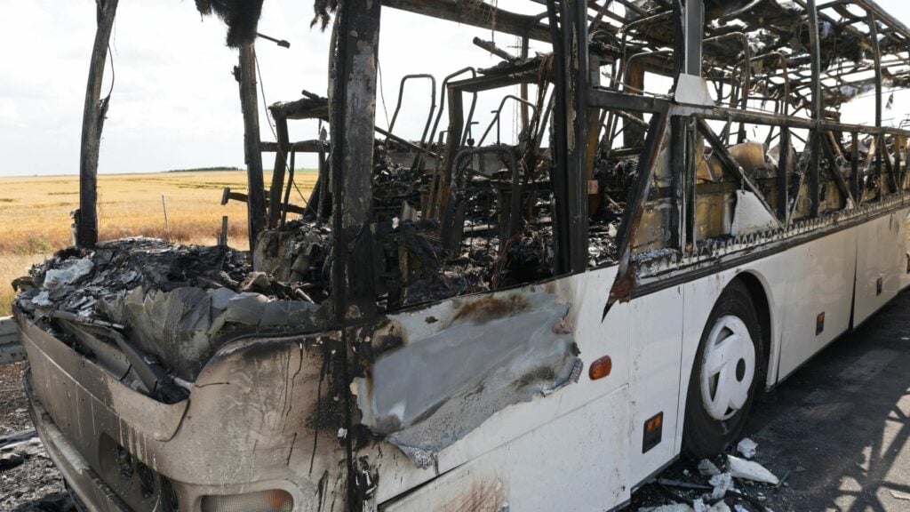 Imagem de um ônibus batido e com vestígios de que foi queimado.