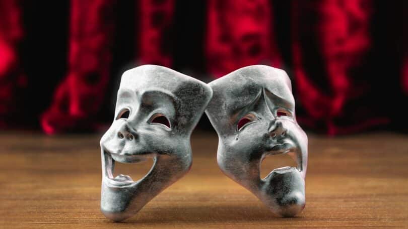 Máscaras de teatro em frente a uma cortina vermelha