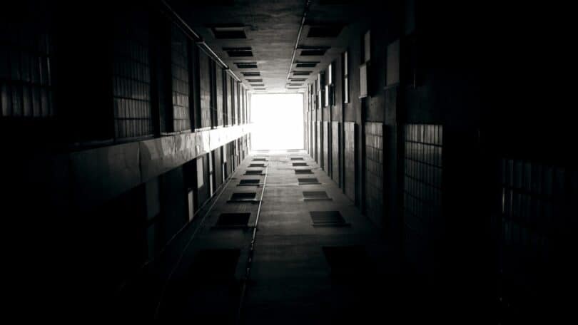 Imagem de um corredor escuro e no fim dele uma porta com uma luz ao fundo.