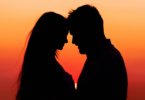 Sombra de casal com as faces encostadas, em fundo laranja de pôr do sol.