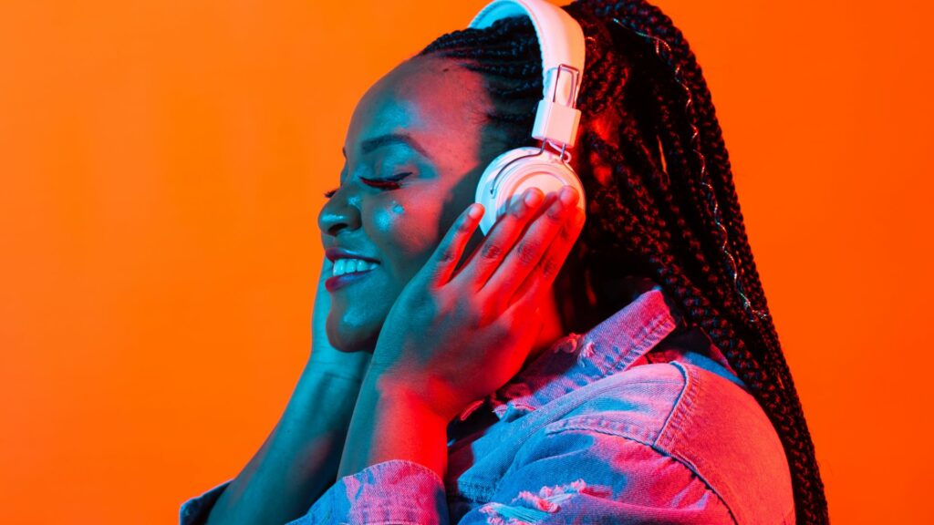 Imagem de fundo em neon de uma jovem negra ouvindo música em fones de ouvido.