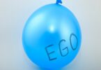 Imagem de fundo cinza e em destaque um balão azul e nele está escrito a palavra EGO.