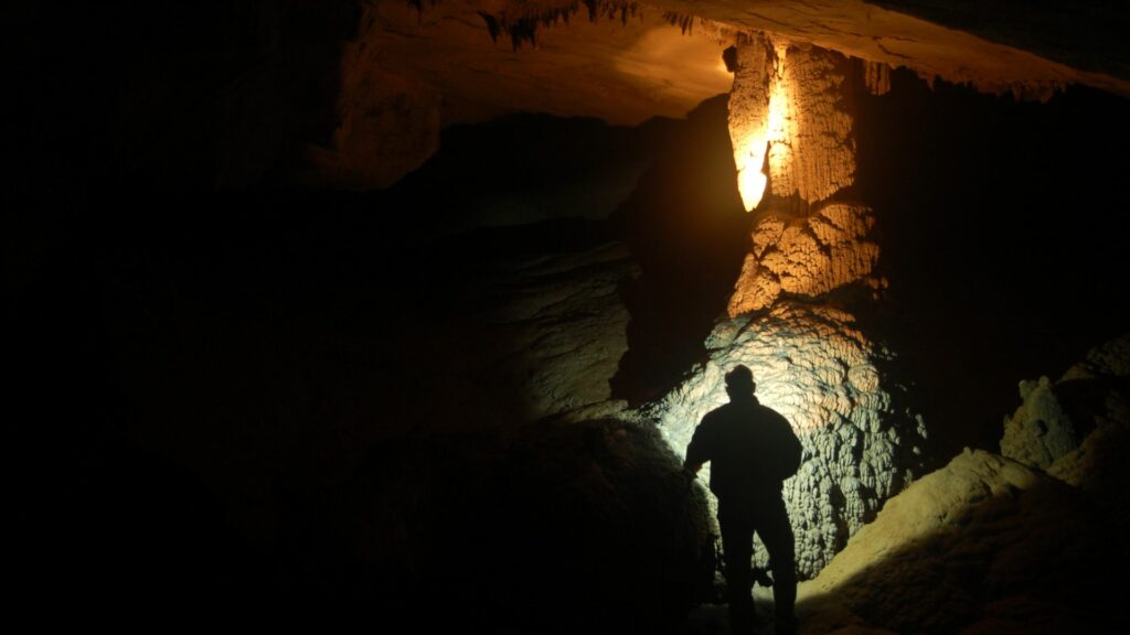 Imagem de um homem explorando uma caverna.
