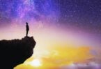 Imagem de um céu estrelado ao anoitecer. Em destaque, a silhueta de um homem sobre uma rocha, olhando para o céu e refletindo sobre o seu propósito de vida.