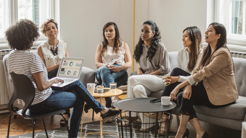 Imagem de várias mulheres reunidos em um espaço de coworking participando de uma reunião de negócios.