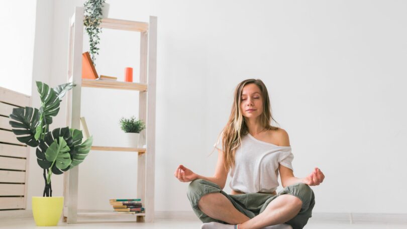 Jovem em posição de lótus enquanto medita. Prática de Mindfulness, Bem-Estar e Autoconhecimento, cuidando da mente e do corpo.