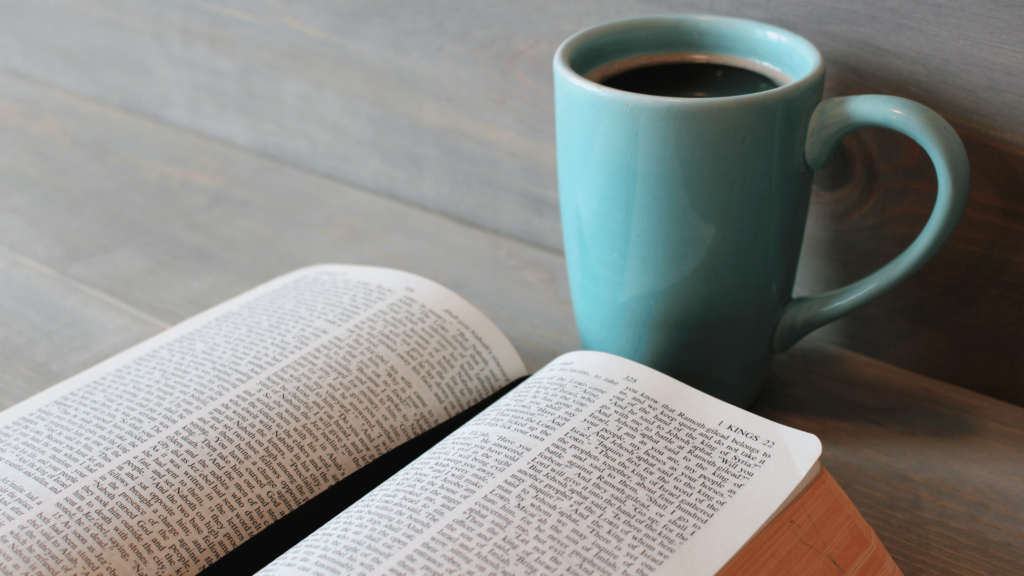 Livro e café sobre mesa de madeira. 