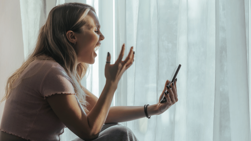 Mulher gritando de raiva enquanto olha no celular. 