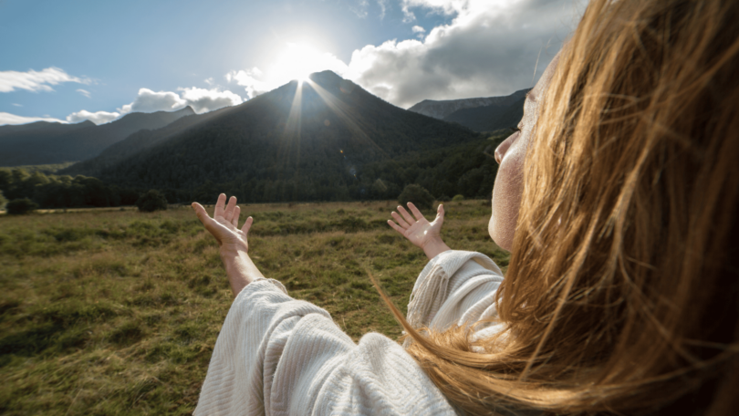 Conceito de Espiritualidade. Mulher sentindo bem-estar ao nascer do sol.