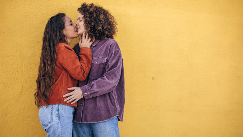 Casal de lésbicas se abraçando e se beijando.