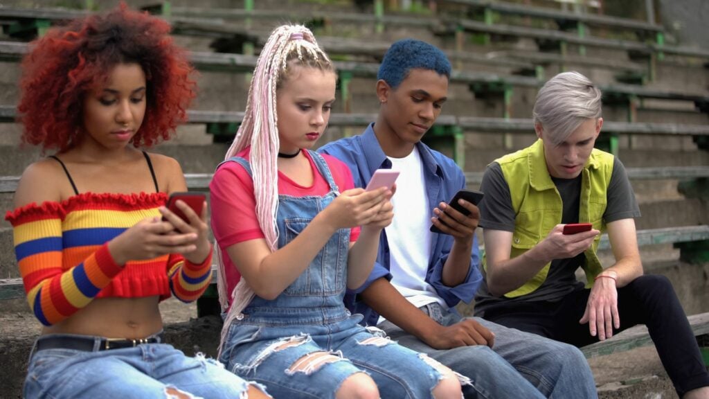 Imagem de vários adolescentes sentados rolando seus smartphones. Retrato da geração Z, totalmente cibernética e de conexão on-line.