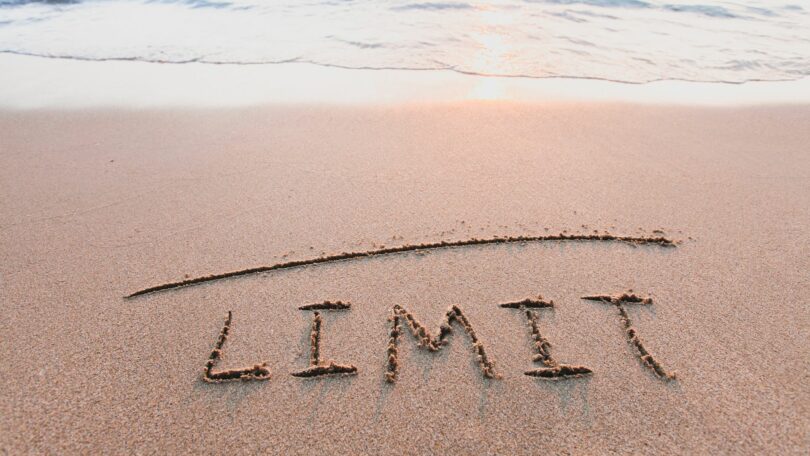 Imagem de uma praia e na areia está escrito a palavra limite em inglês.