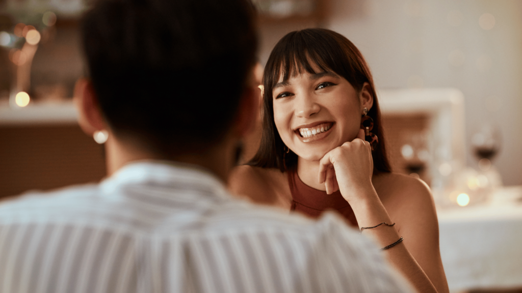 Mulher sorrindo para homem durante encontro. 