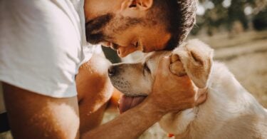 Imagem de um homem abraçando o seu cachorro caramelo