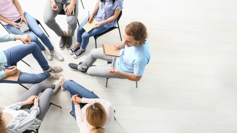 Imagem de várias pessoas reunidas em uma sessão de terapia de grupo