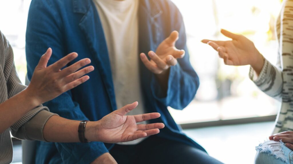 Imagem de três pessoas em uma roda de conversa, trazendo o conceito de ajuda e apoio emocional.
