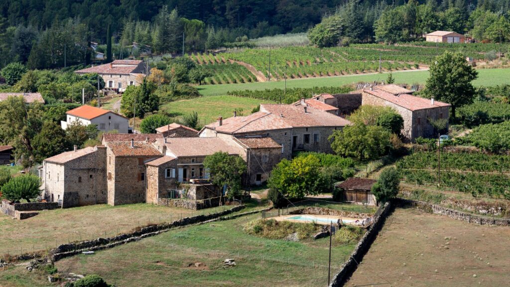 Imagem de um pequeno vilarejo na França, rodeado por muito verde.
