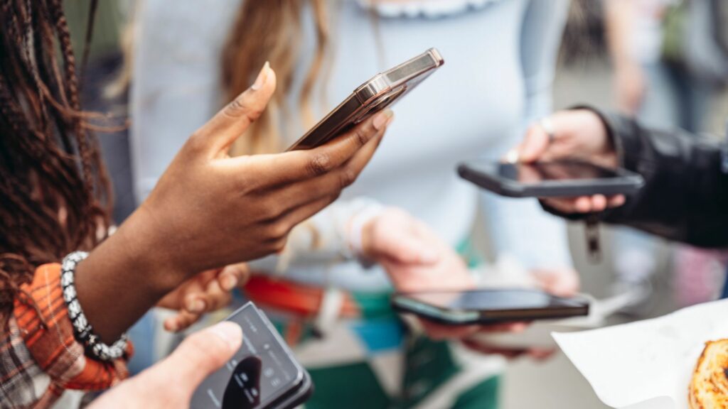 Imagem de vários jovens da Geração Z segurando smartphones usando as mídias sociais.
