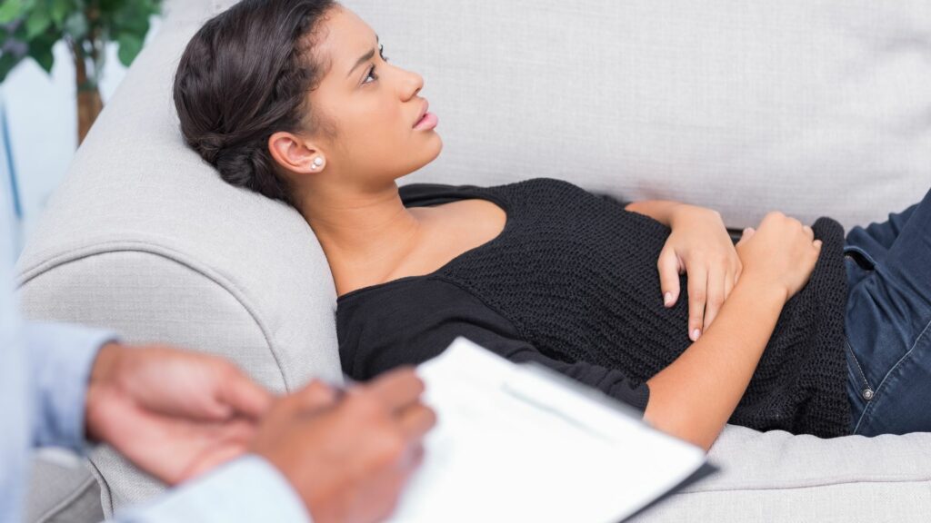 Imagem de uma mulher deitada em um sofa, conversando com a sua terapeuta durante uma sessão de terapia.
