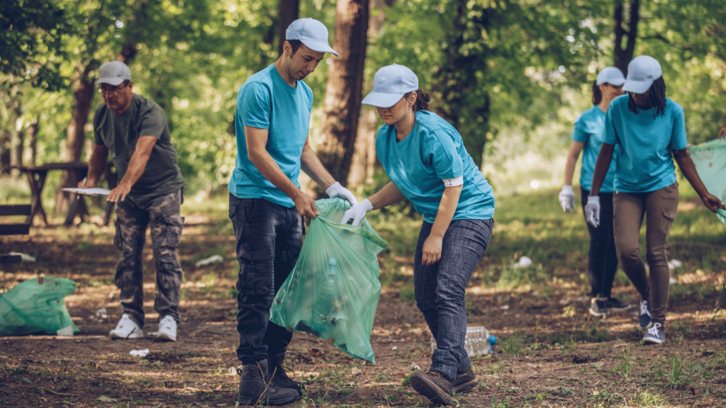 Um grupo de cinco voluntários está coletando lixo em um parque.